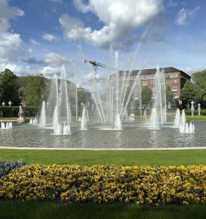 ein Brunnen inmitten eines Parks mit Blumen