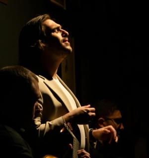 ein Mann, der in einem dunklen Raum sitzt und eine Krawatte hält