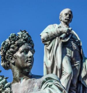 Una estatua de una mujer parada frente a un cielo azul.