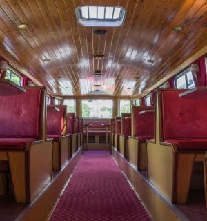 ein Zugwaggon mit roten Sitzen und einem rosa Teppich