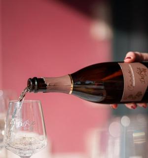 en person, der hælder en flaske vin i et glas