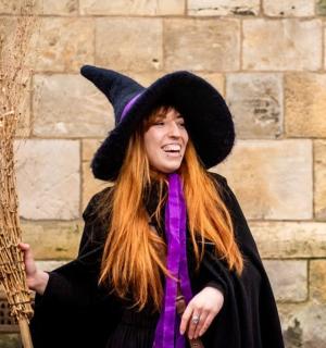 a woman in a witch hat holding a broom