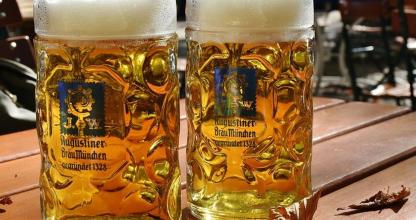 two glasses of beer sitting on a wooden table