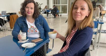 two women sitting at a blue table with a meal