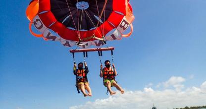 two people are hanging from a parachute in the water