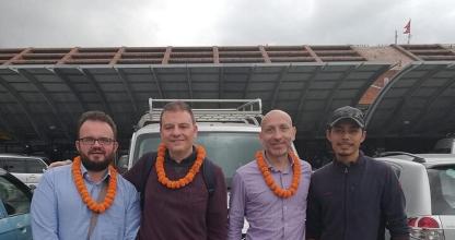 a group of three men standing in front of a parking lot
