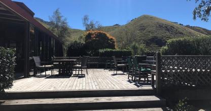 a patio with chairs and tables with a mountain in the background