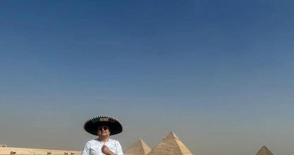 Un hombre con sombrero parado frente a las pirámides.