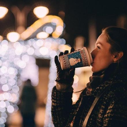 a woman drinking from a coffee cup at night