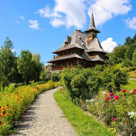 a path in front of a building with flowers