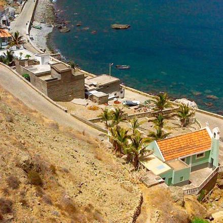 a house on the side of a hill next to the ocean