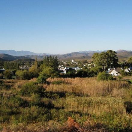 a field of grass with houses and mountains in the background