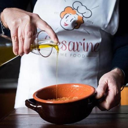 a person pouring sauce into a bowl in a kitchen