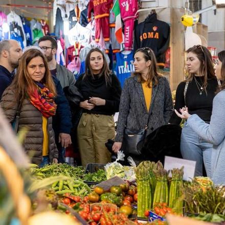 a group of people standing in a market with vegetables
