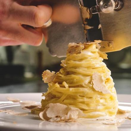 una persona che taglia un pezzo di cibo su un piatto