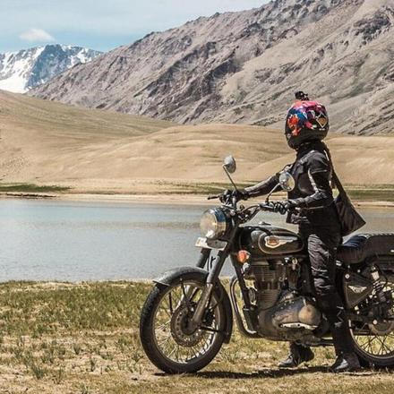 a person sitting on a motorcycle in front of a mountain