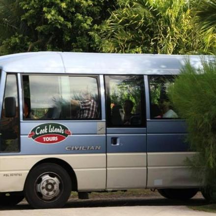 a blue and white bus parked next to a bush