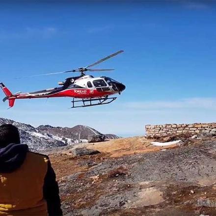 a red and white helicopter flying over a mountain