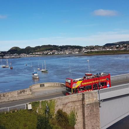 a red bus on a bridge over a river