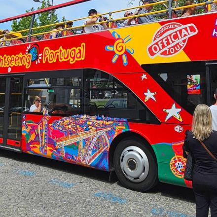 ein roter Doppeldeckerbus mit Menschen, die daneben stehen