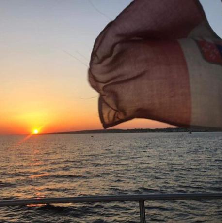 Una bandera en un crucero con la puesta de sol de fondo