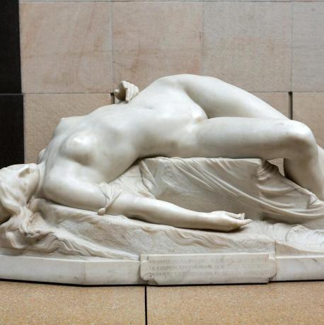 una estatua de una mujer desnuda recostada sobre una almohada