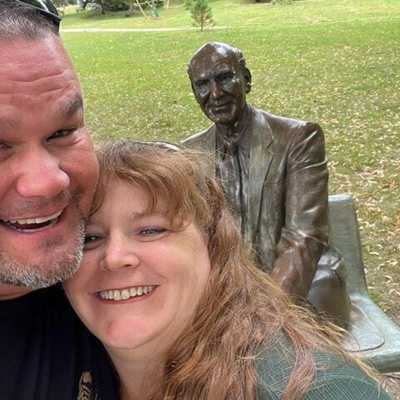 a man and a woman standing next to a statue