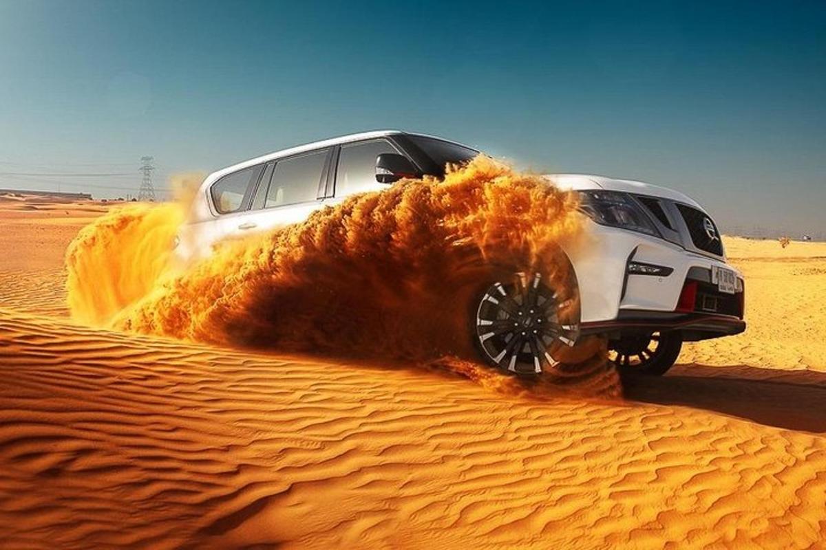 un'auto bianca che guida sulla sabbia del deserto