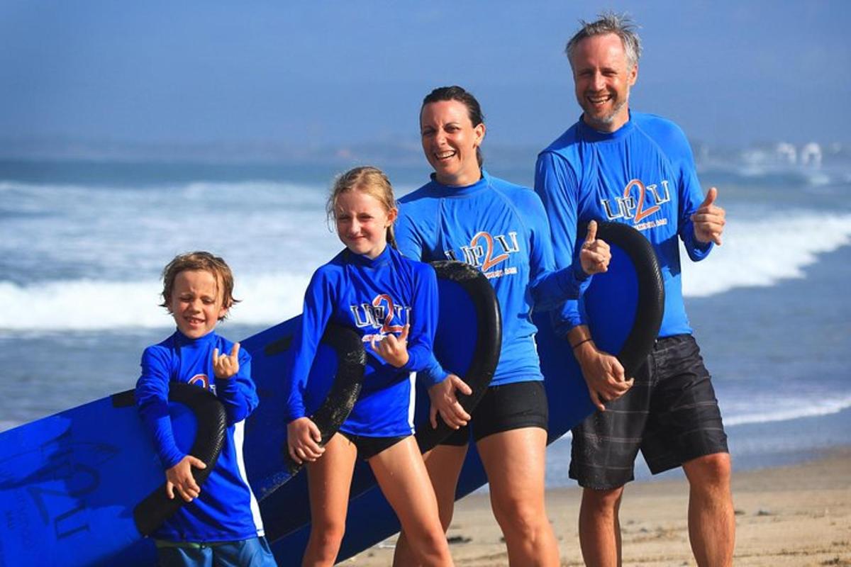 a group of people standing on the beach with a surfboard