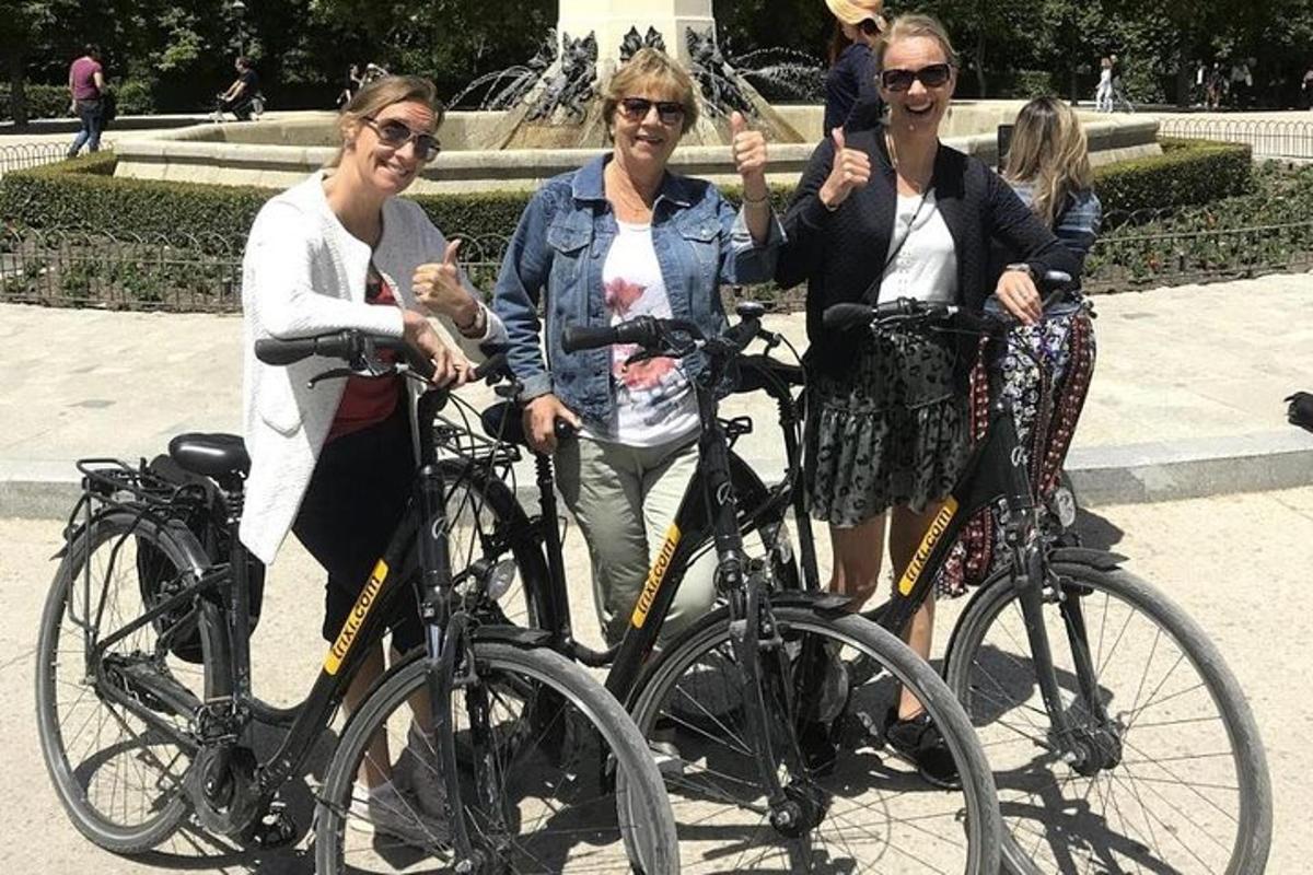 Kolme naista poseeraa polkupyöriensä kanssa suihkulähteen edessä