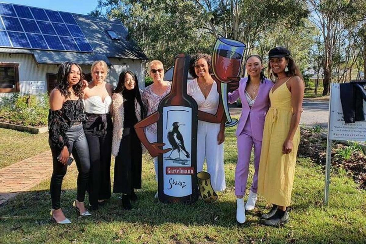 a group of women standing next to a bottle of wine