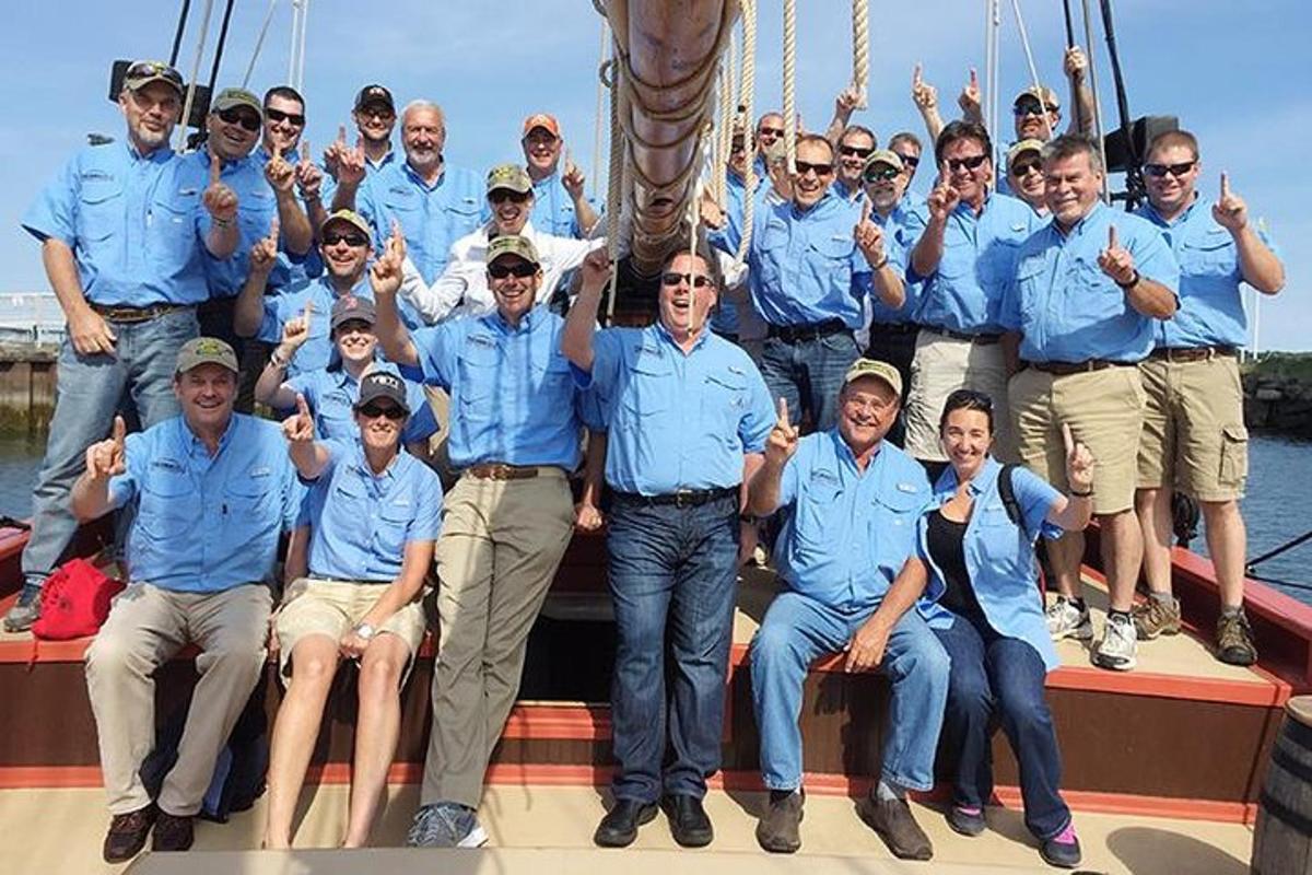 um grupo de homens de camisas azuis posando em um barco