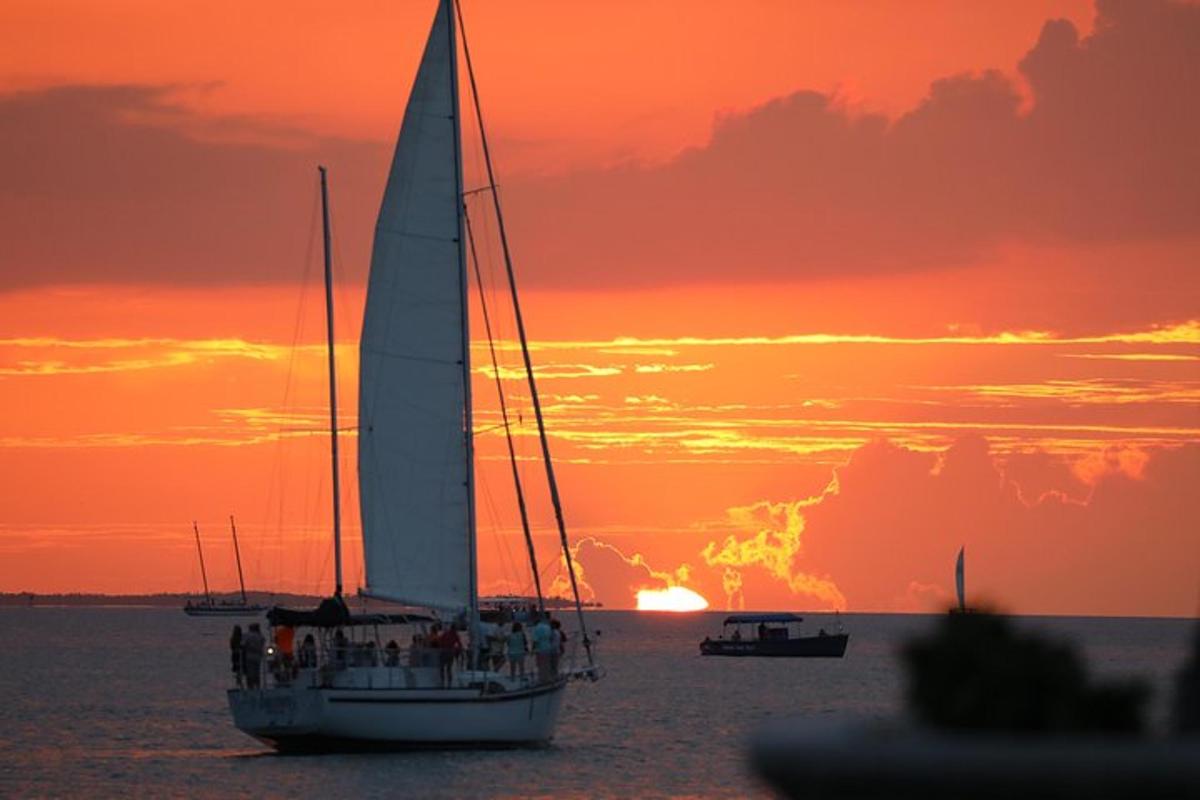 a sail boat in the water with a sunset