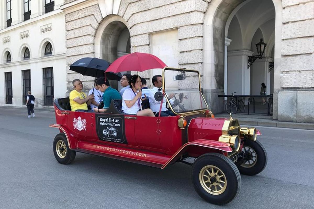 un gruppo di persone in viaggio su un'auto rossa con gli ombrelli