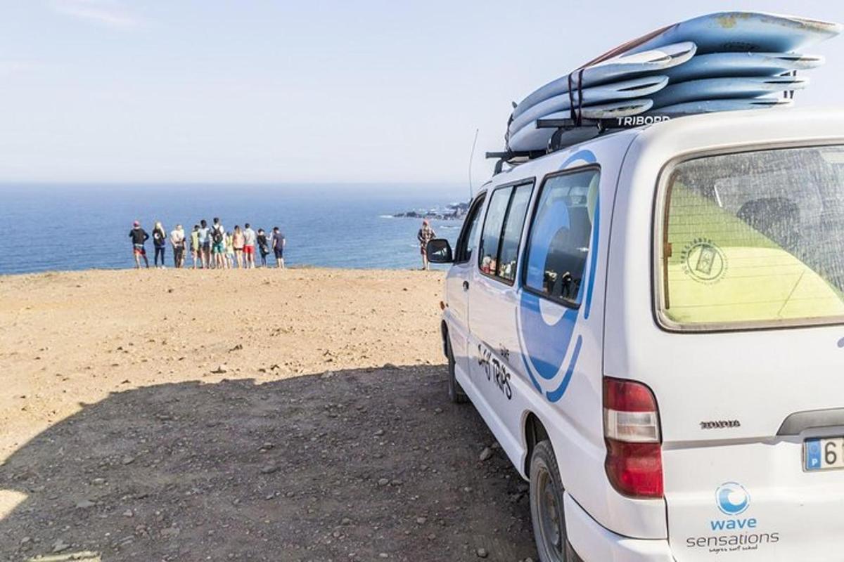 sebuah van putih diletakkan di pantai dengan papan luncur di atasnya