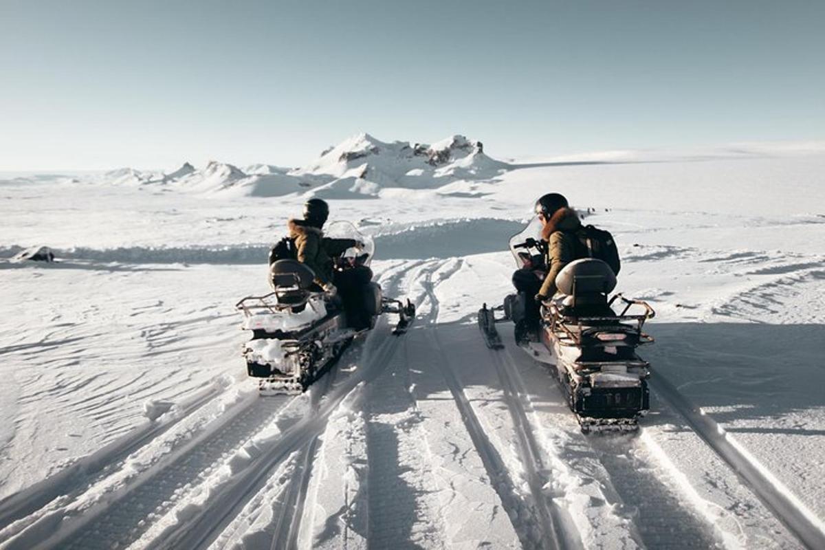 tres persones conduint quads a la neu