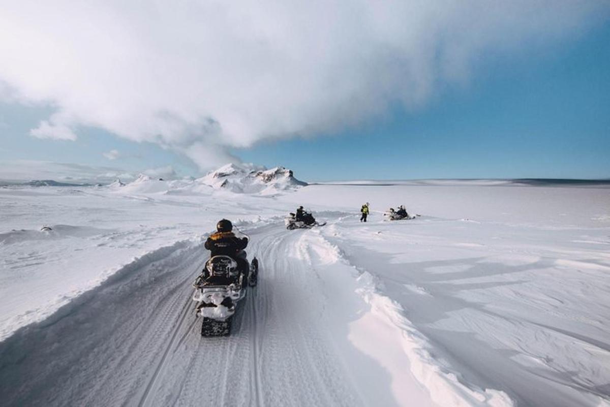un grup de persones que viatgen en motos de neu a la neu