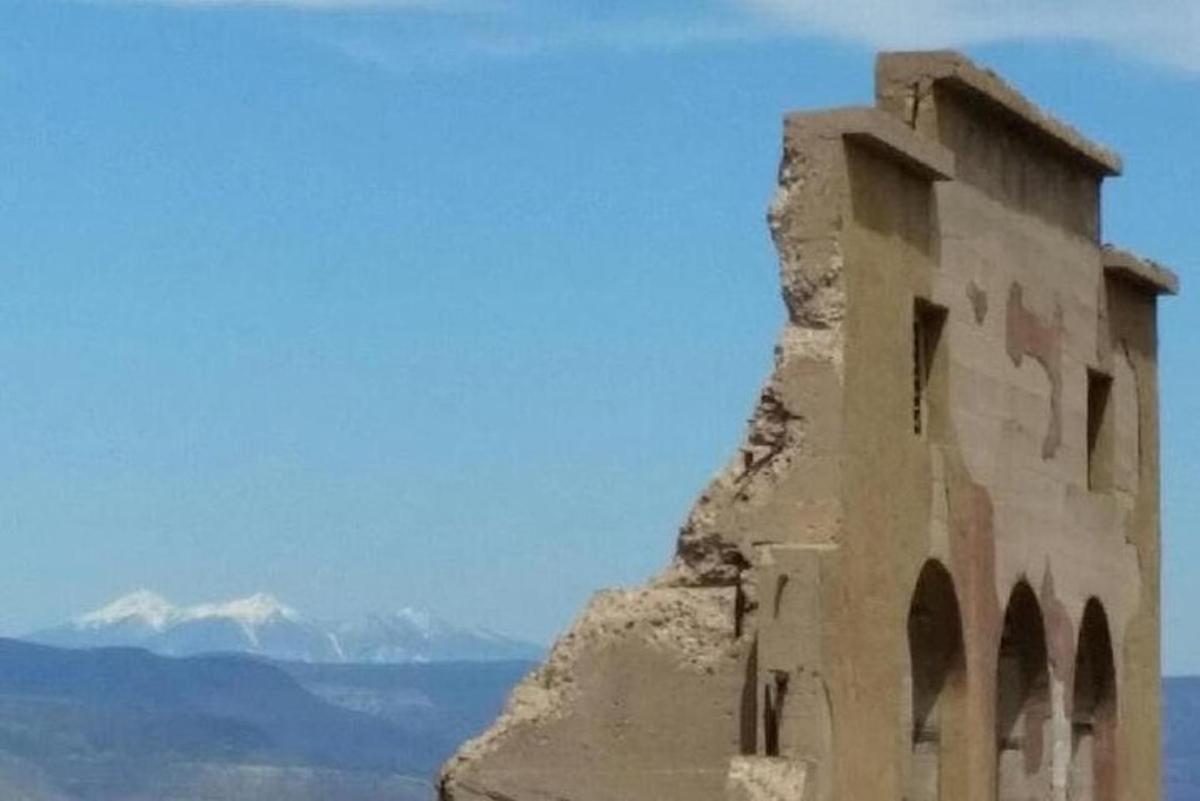 a building on the side of a cliff with mountains in the background