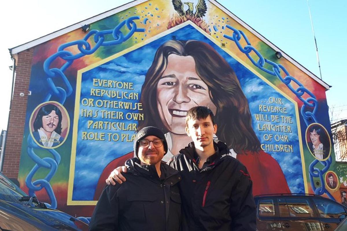 two men standing in front of a mural