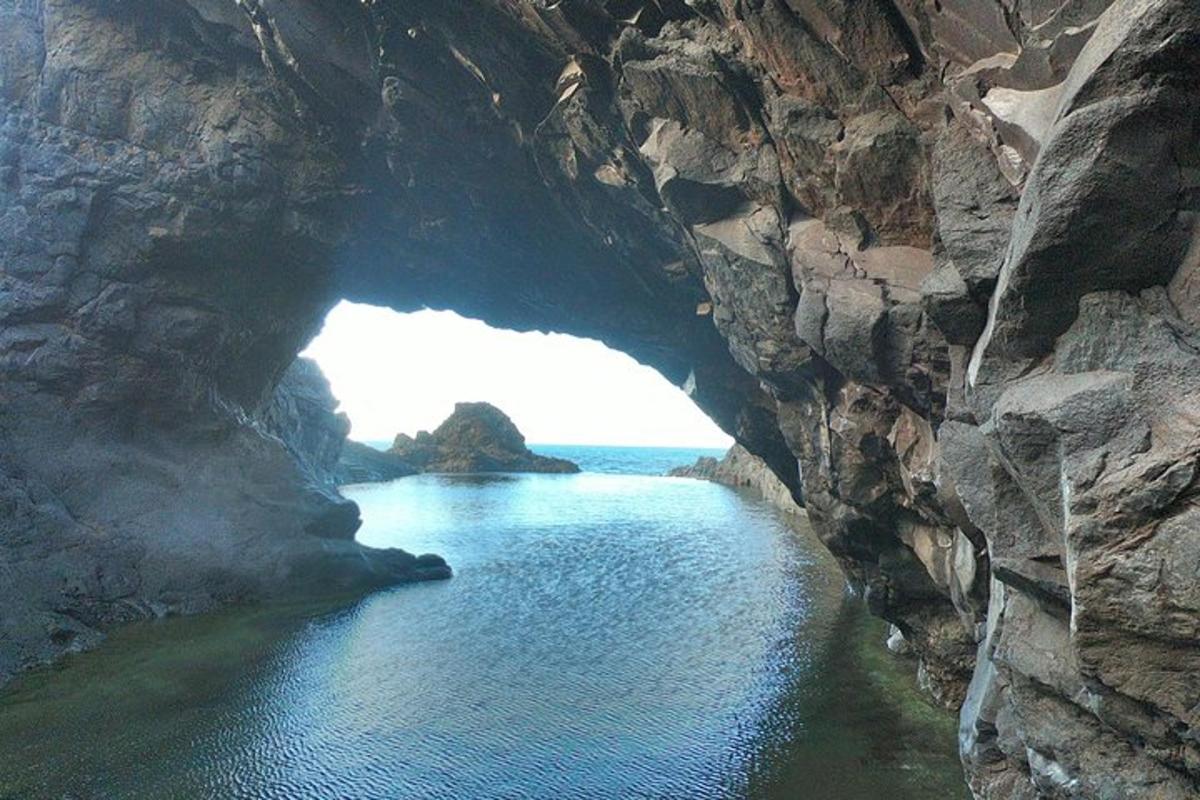 a cave in a rocky mountain with the ocean