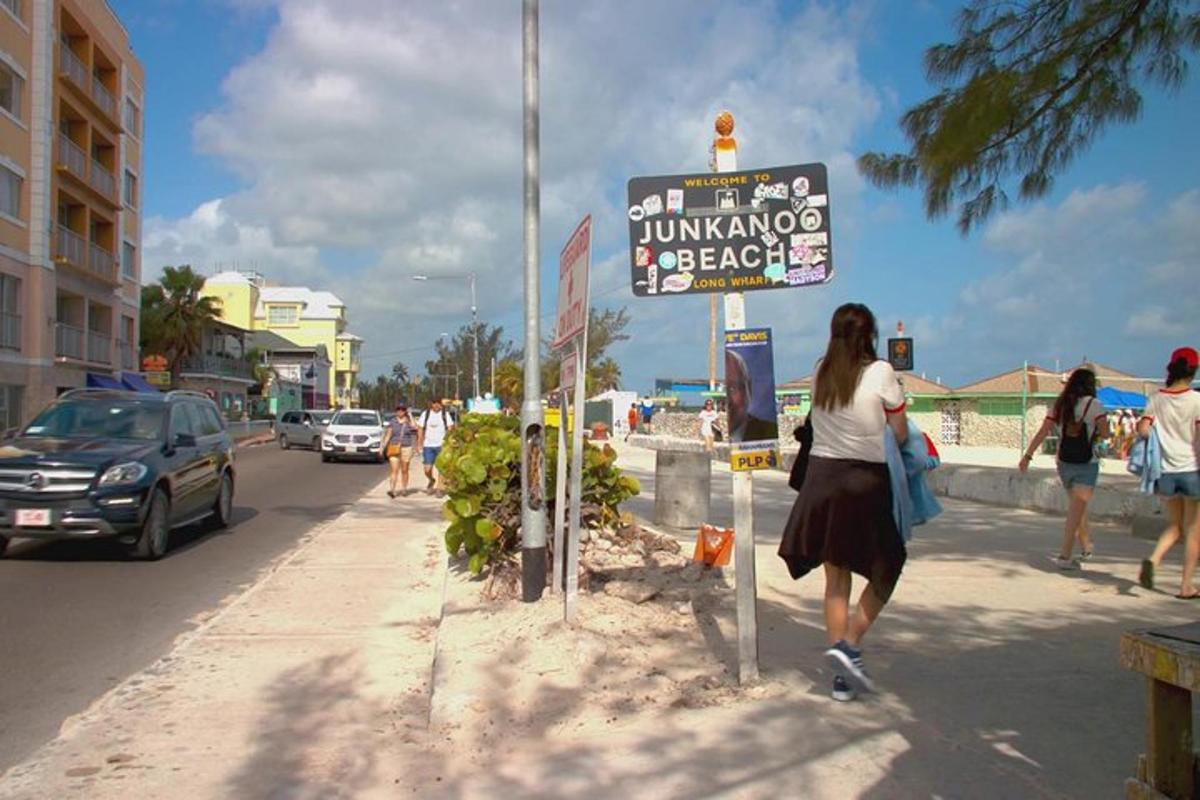 a woman walking past a sign on the side of a street