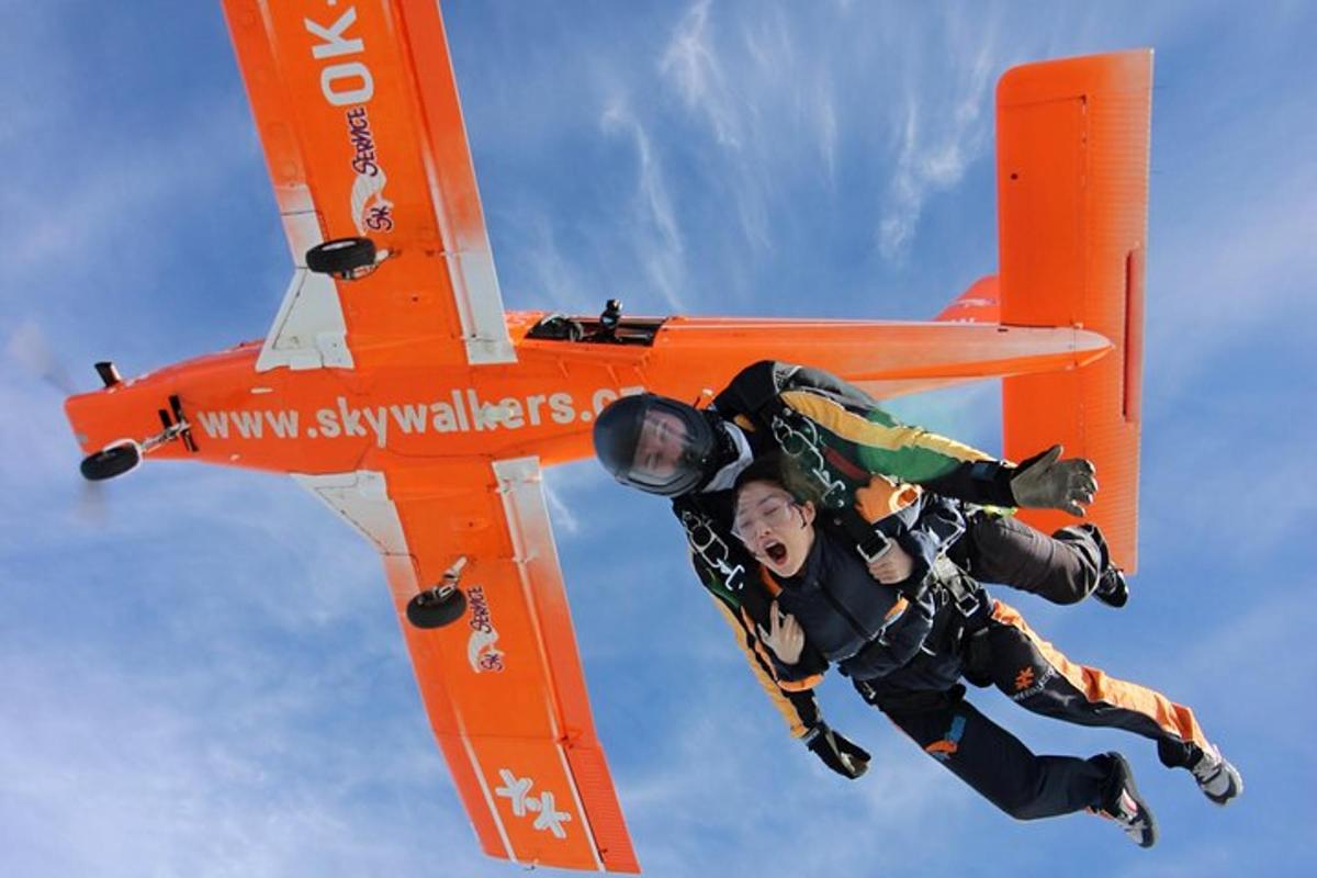 un uomo che pilota un aereo arancione nel cielo