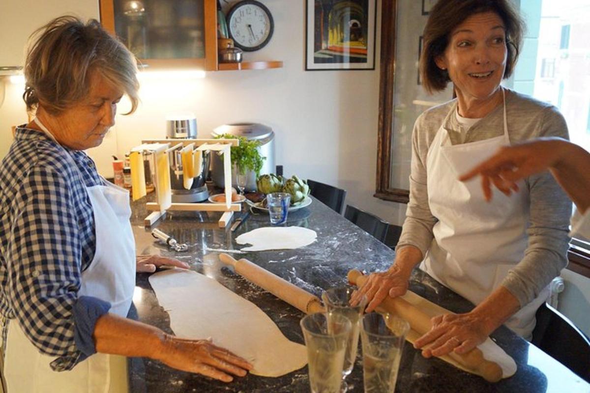 two women standing in a kitchen preparing dough