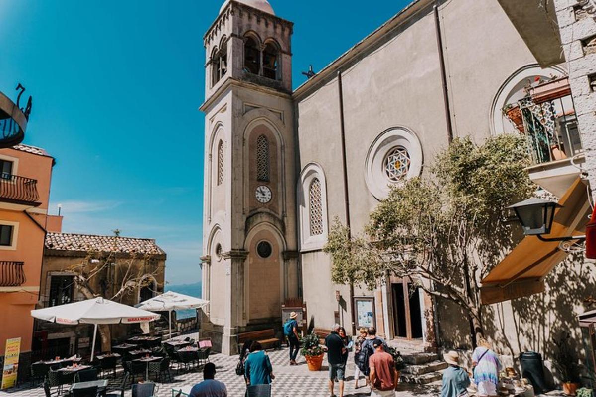 una chiesa con una torre dell'orologio e persone che camminano davanti ad essa