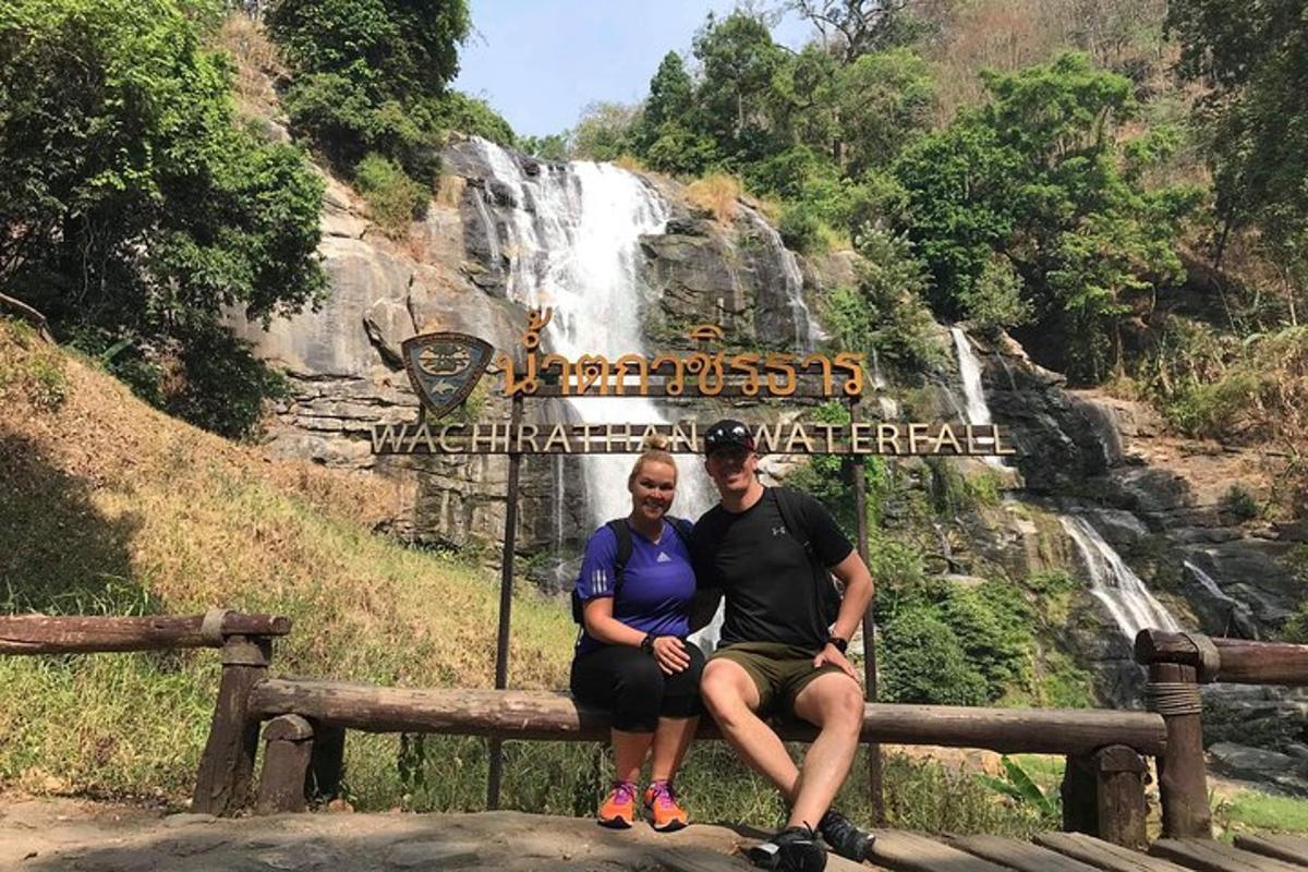 een man en een vrouw zitten op een bankje voor een waterval