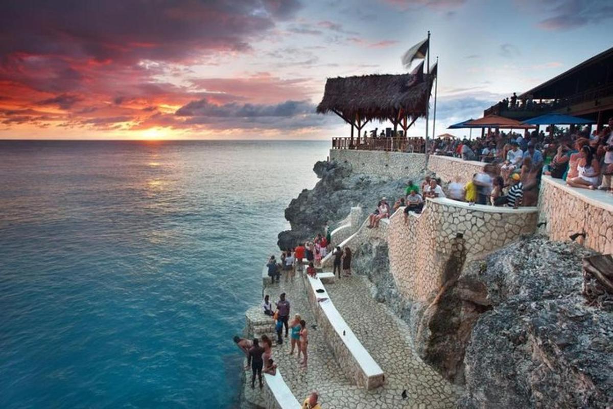 a group of people standing on a cliff near the ocean