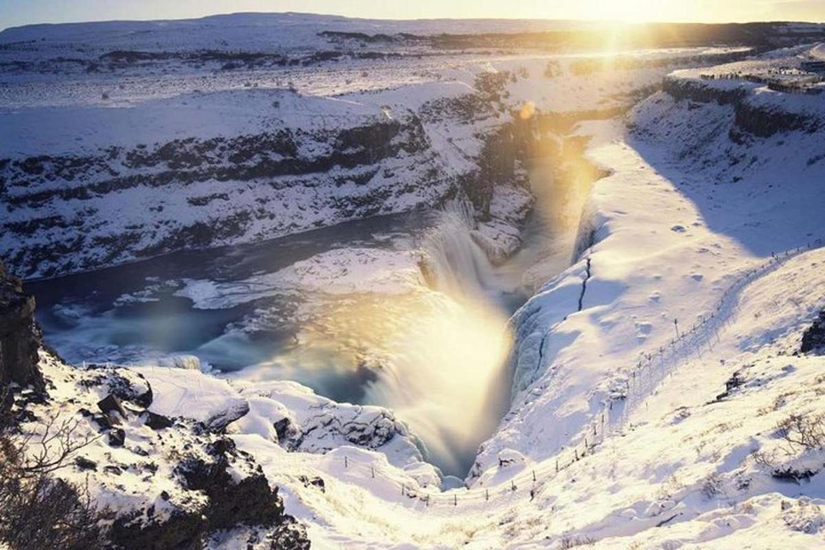 водопад в снега със слънце на заден план