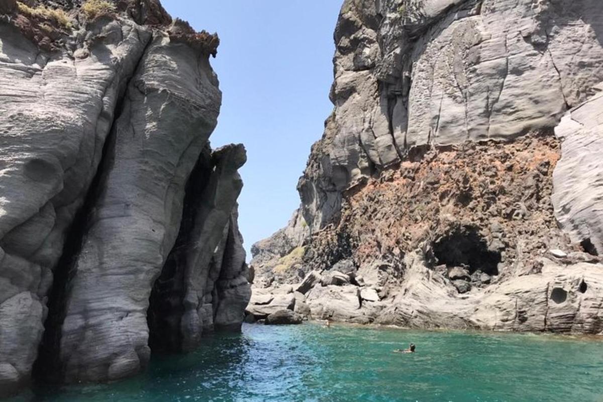 osoba plavající ve vodní ploše vedle útesu