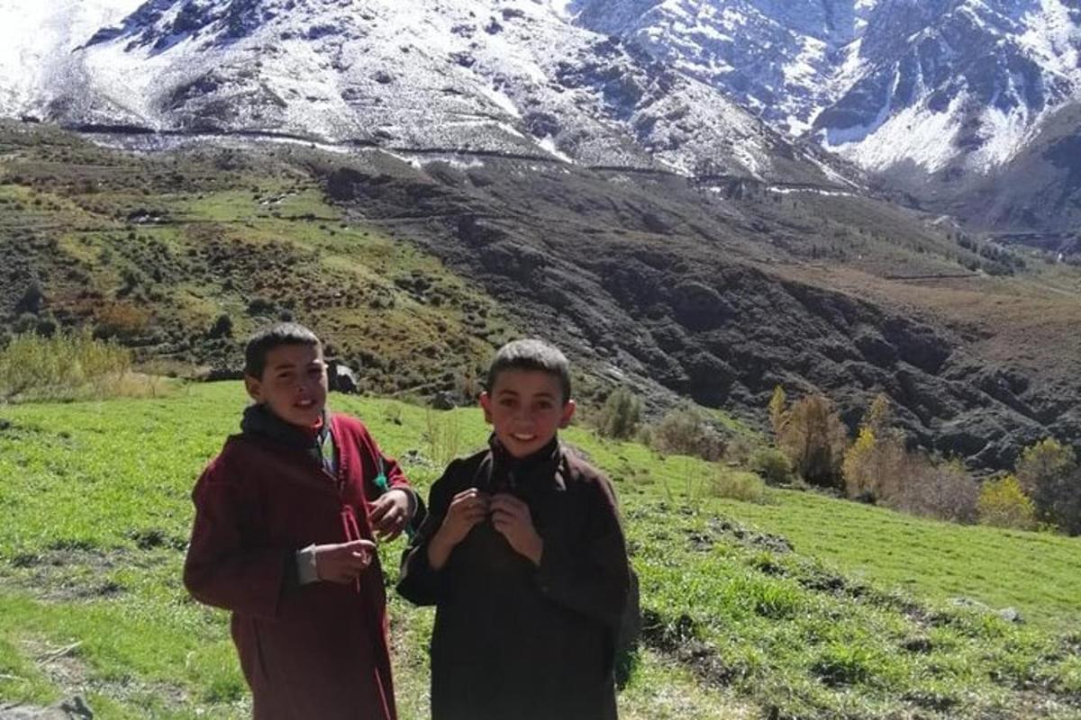 two boys standing in a field with a mountain in the background