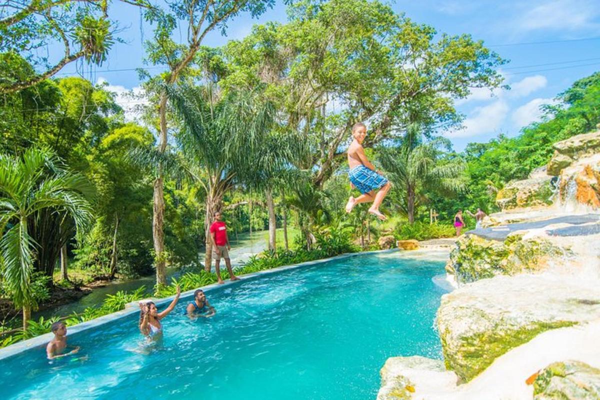 Un niño saltando a una piscina en un complejo turístico.